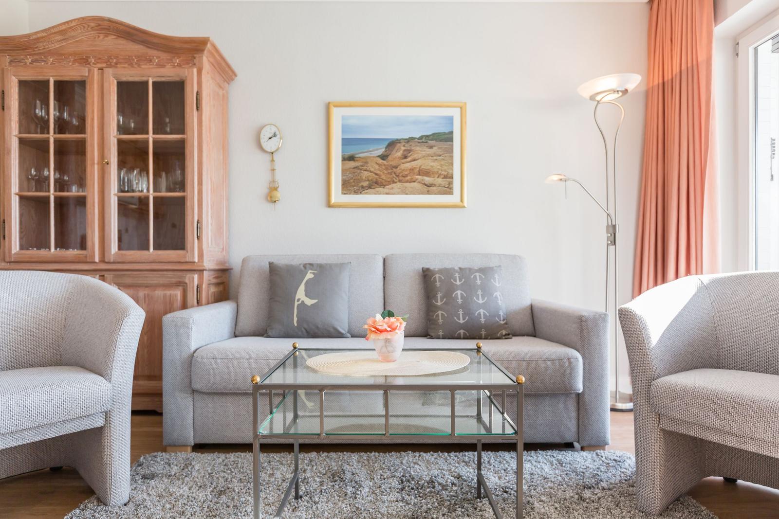 Living room with gray sofa, two chairs, and glass table.