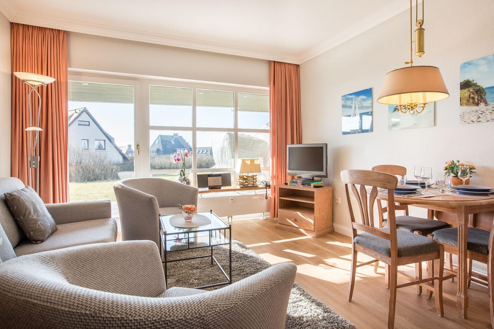 Living and dining area with window, table, chairs, and TV.