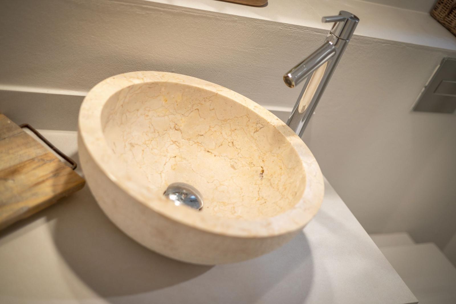Stone basin with modern faucet on a simple countertop.