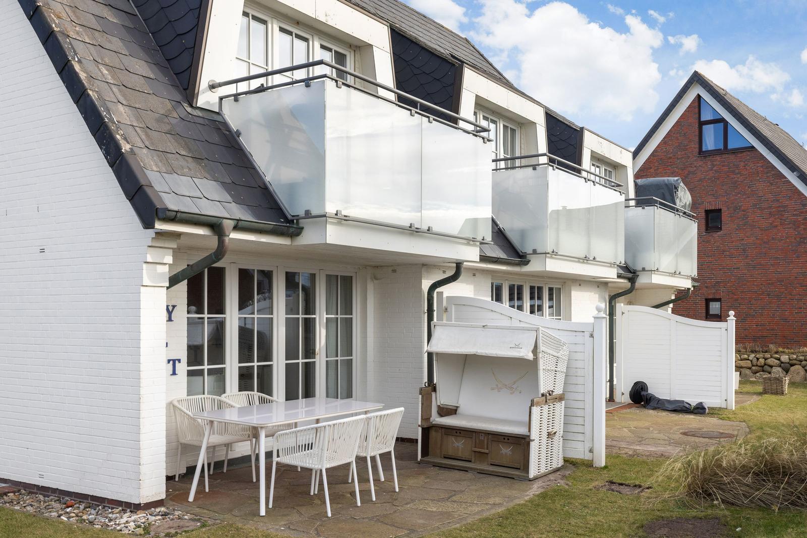 House with balconies, terrace, and white garden furniture set.