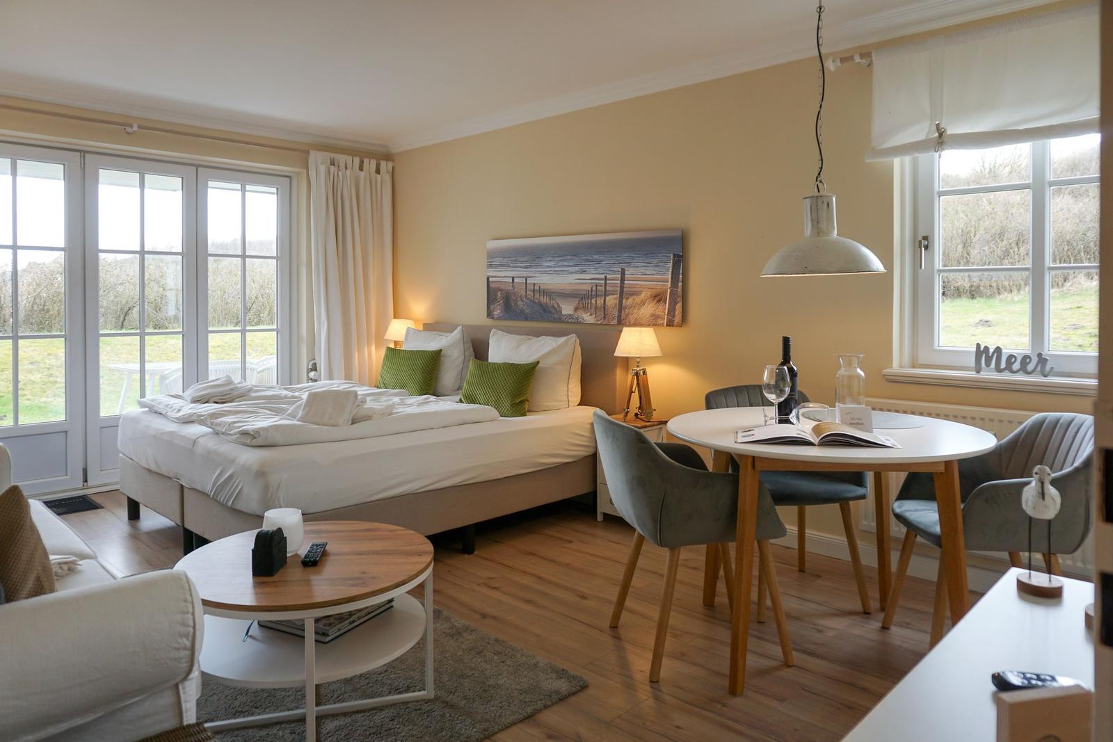 Bedroom with bed, dining table, and view of green field.