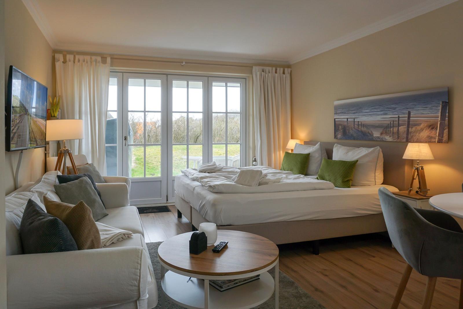 Bedroom with bed, sofa, TV, and window with view.