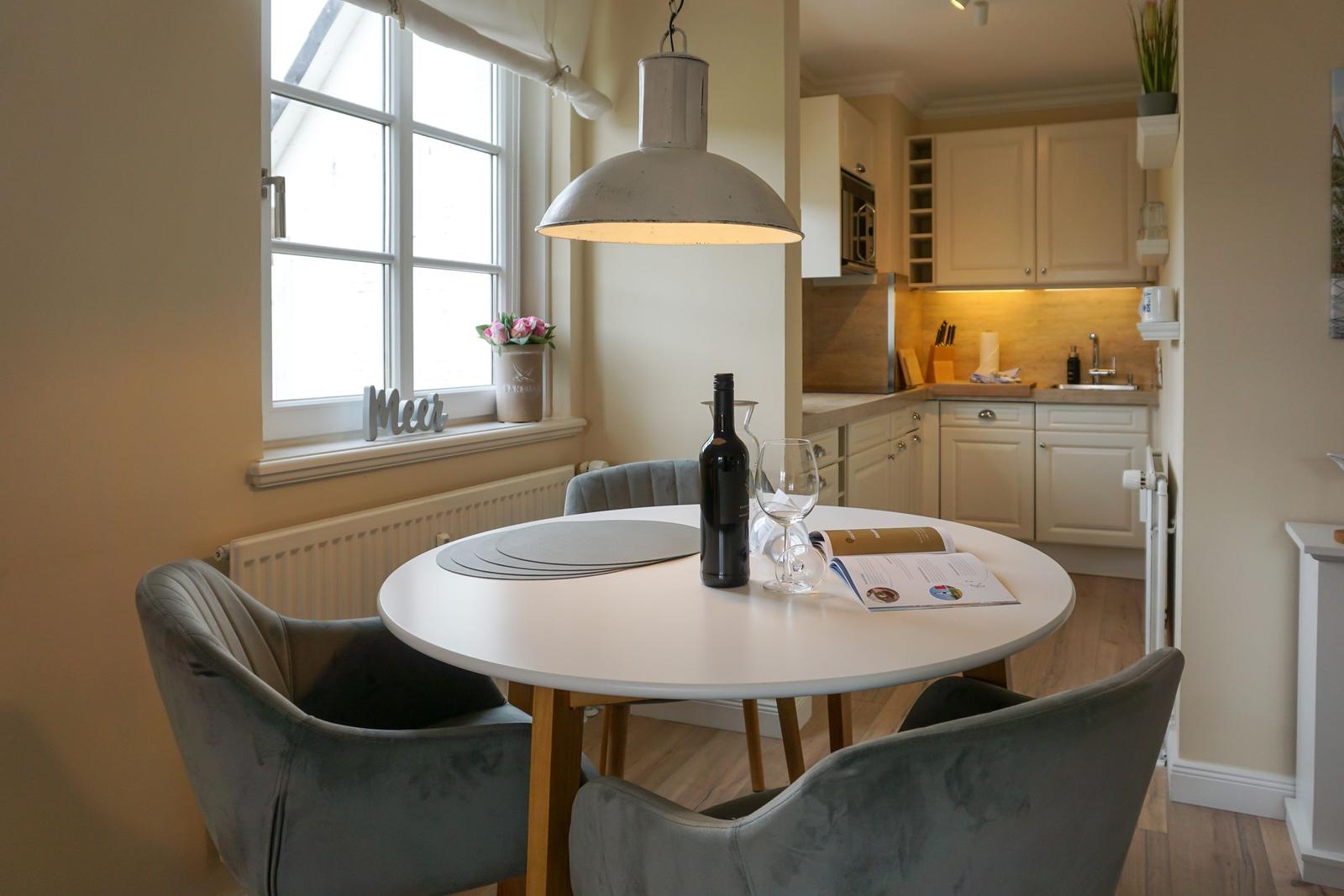 Round table with chairs, wine, and light above the table