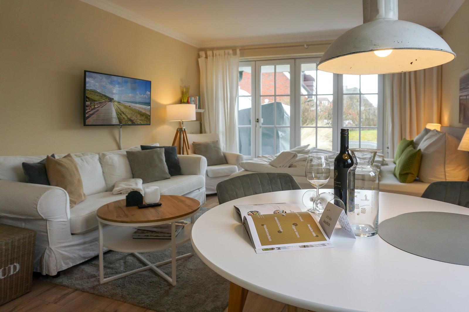 Living and dining area with sofa, TV, and table. Doorway to the garden.