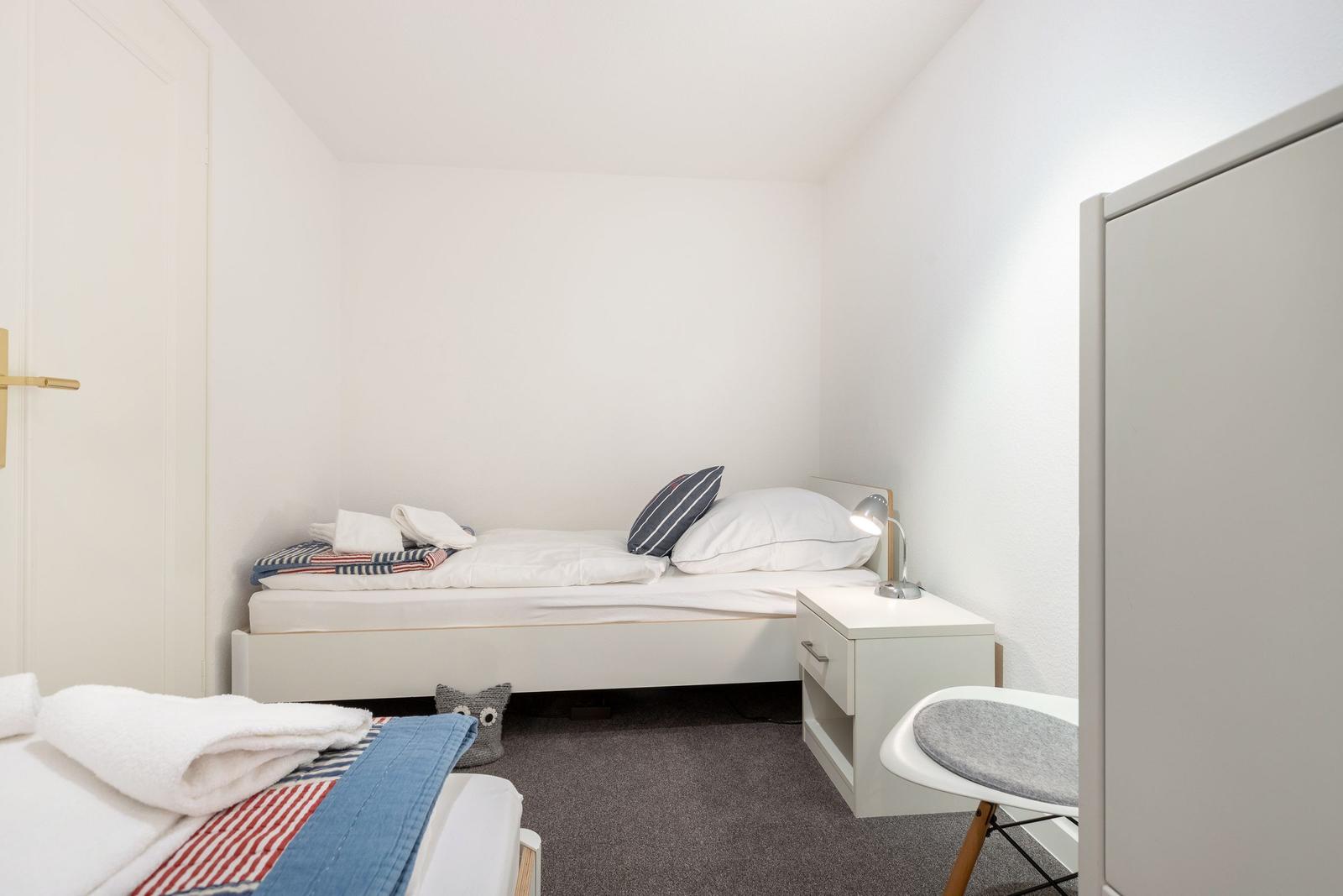 Ein Schlafzimmer mit Bett, Nachttisch, Stuhl und Kleiderschrank.