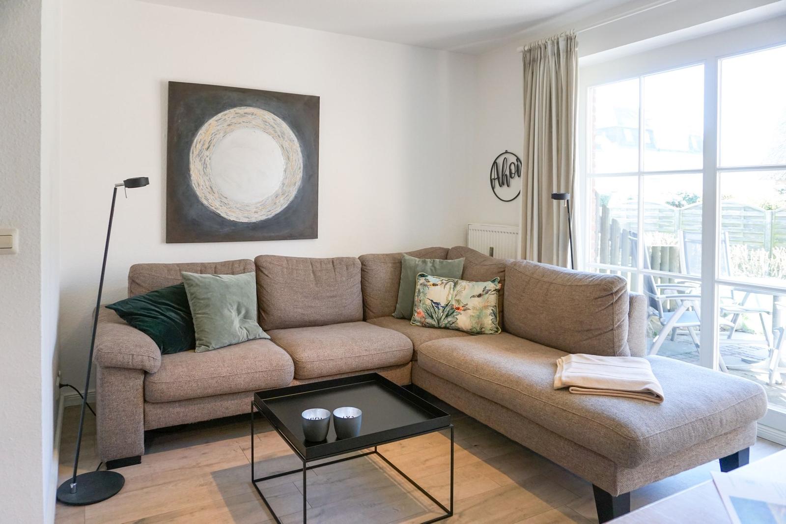 Wohnzimmer mit Ecksofa, Couchtisch und Fenster zur Terrasse.