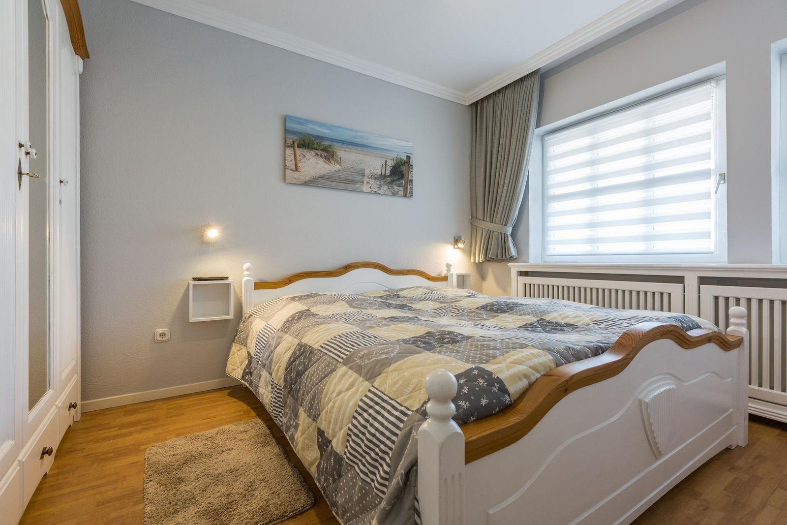Schlafzimmer mit Bett, Wandbild und Fenster mit Jalousie.