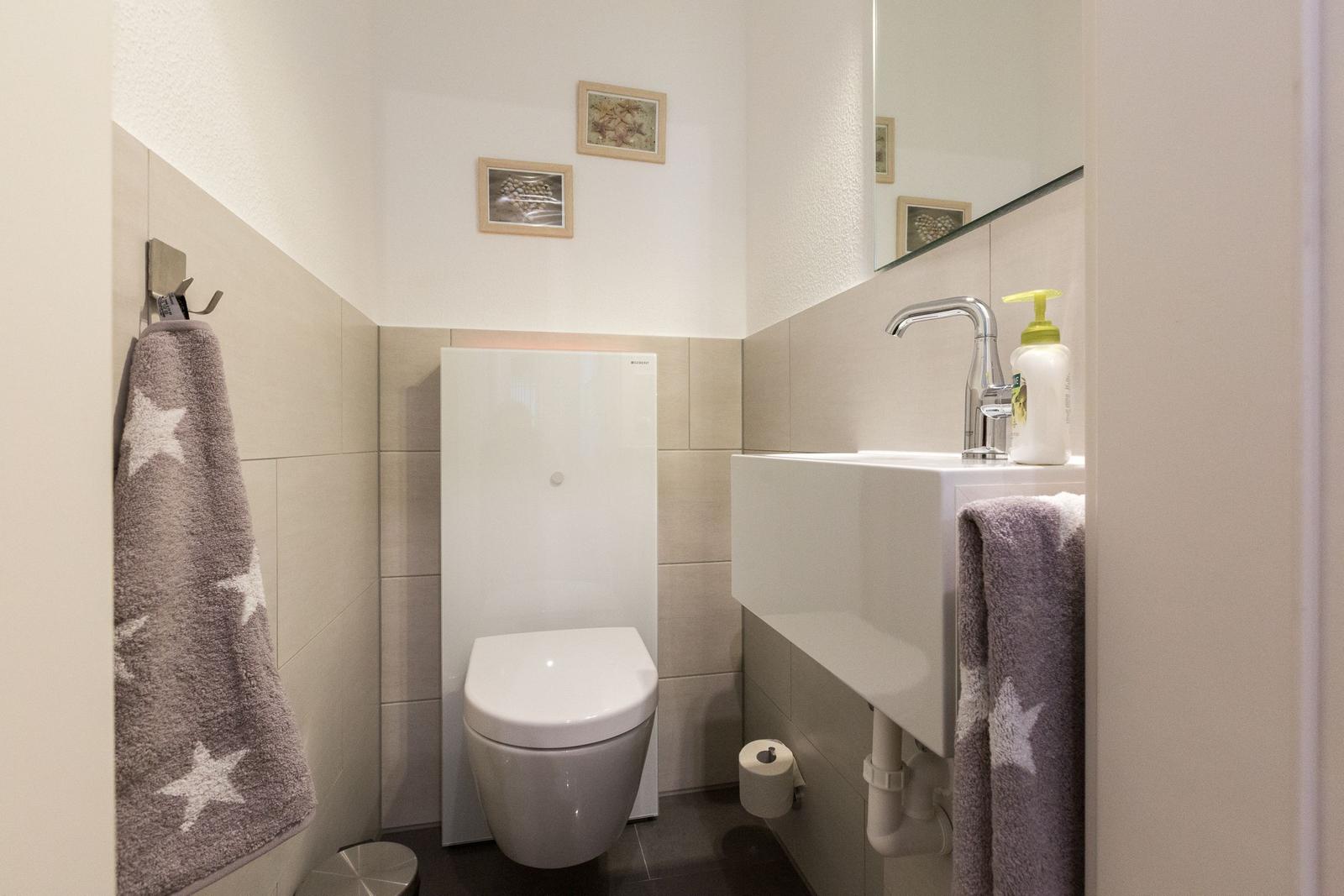 Badezimmer mit Toilette, Waschbecken und Handtuchhalter
