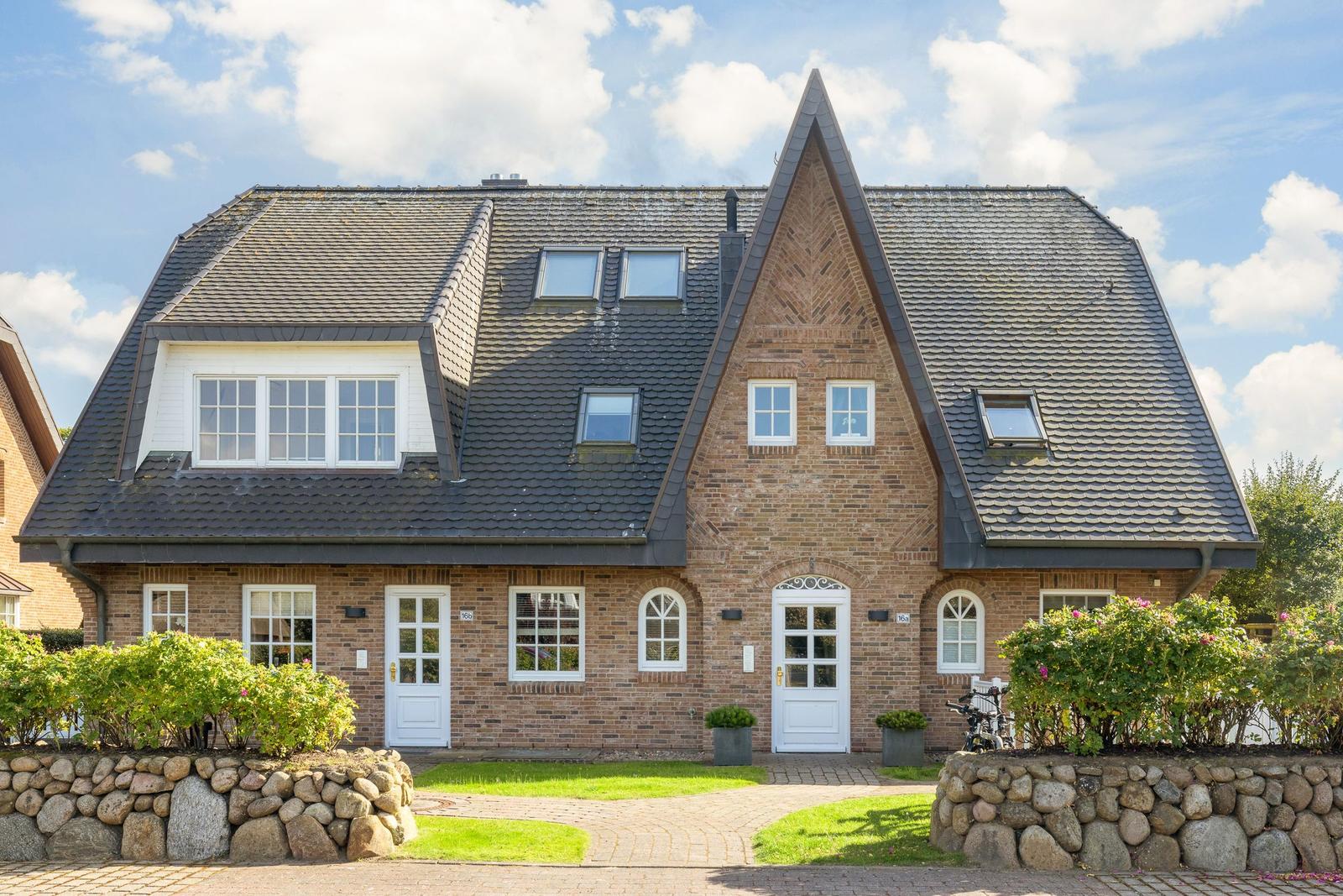 Zwei Eingänge und mehrere Fenster in einem Backsteinhaus mit Schieferdach.