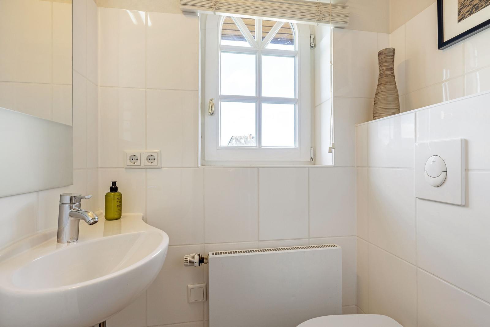 Badezimmer mit Waschbecken, Spiegel und Fenster