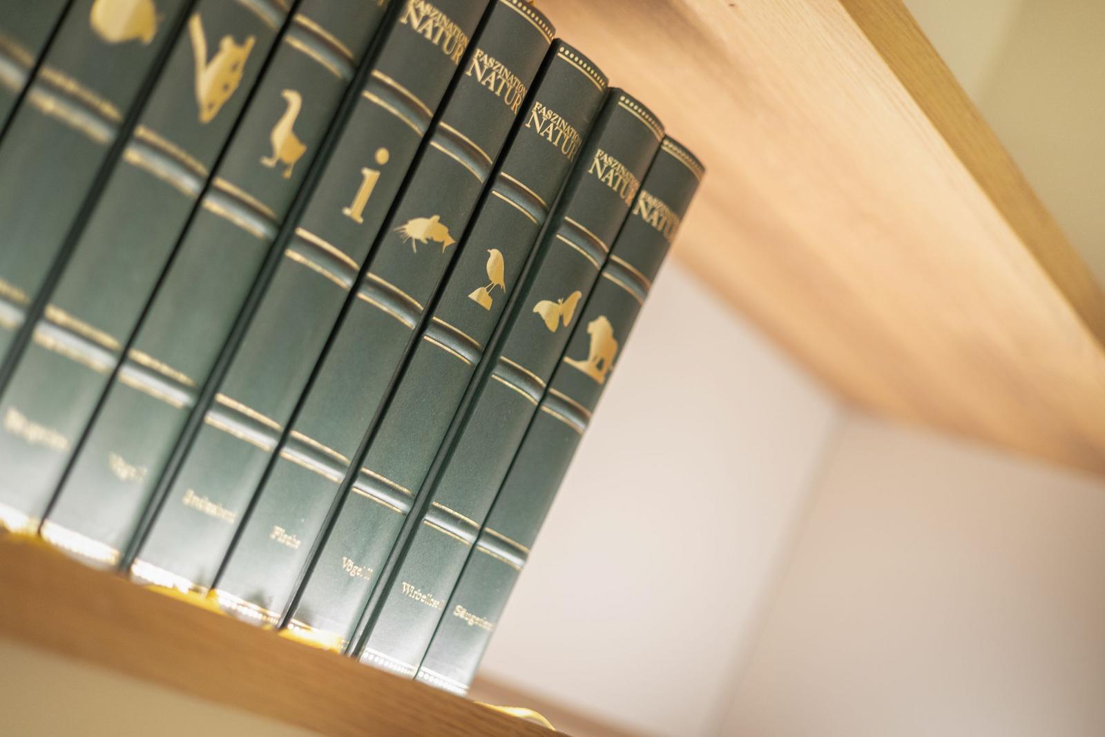 Reihe von Naturbüchern mit goldenen Tiermotiven auf Holzregal