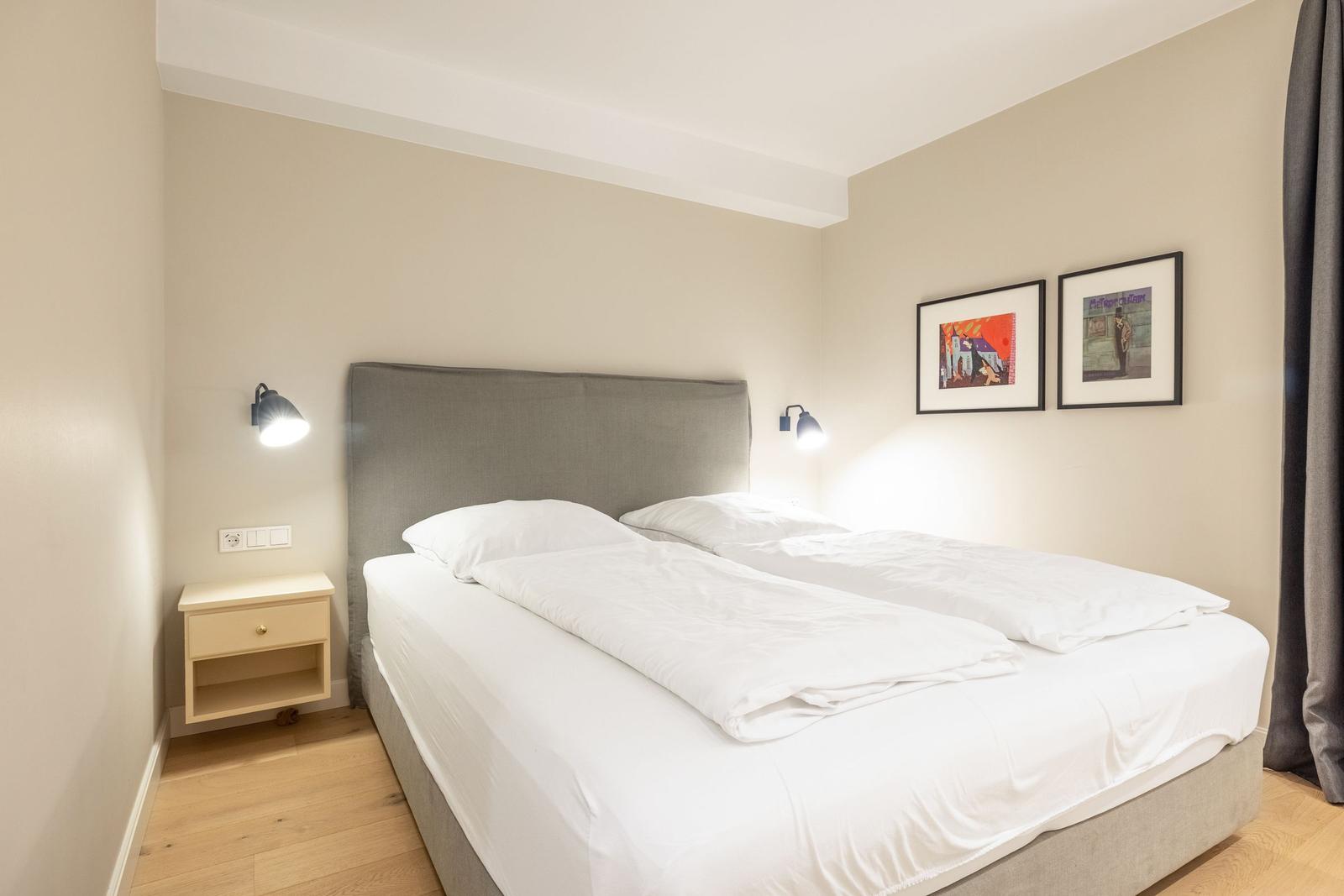 Schlafzimmer mit Doppelbett, Nachttisch und Wandlampen.