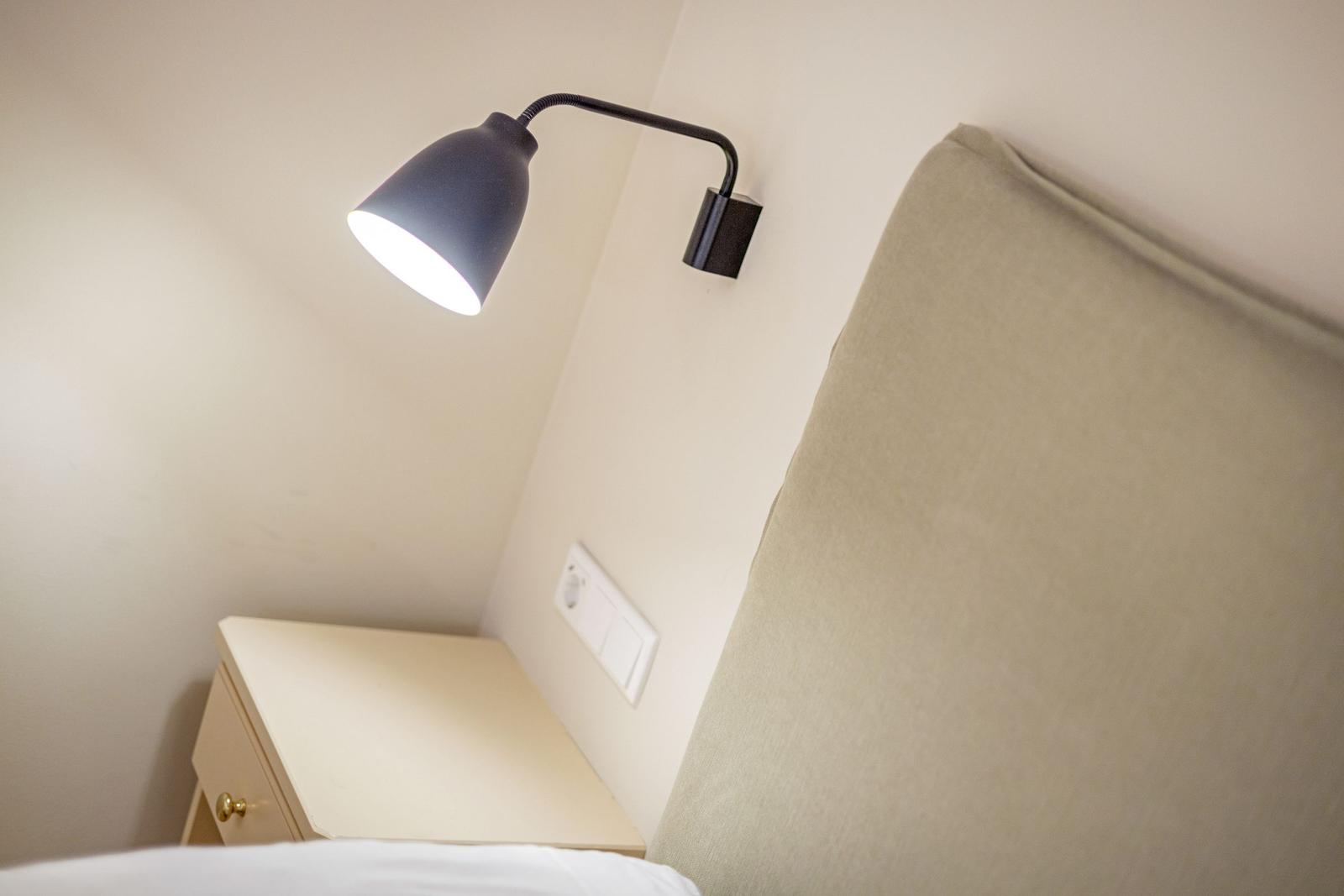 Schlafzimmer mit Nachttisch und Wandlampe.