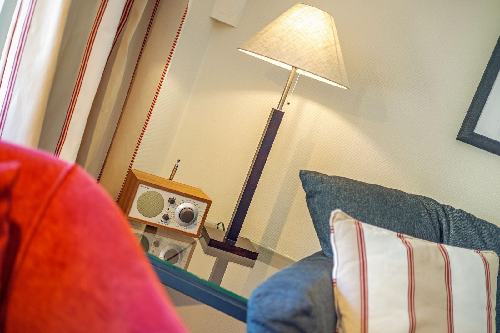 Lampe, Radio und Kissen auf Glasplatte neben Sofa