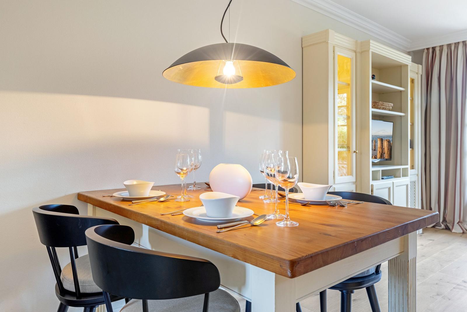 Holztisch mit Stühlen, Deckenleuchte und Sideboard im Essbereich.