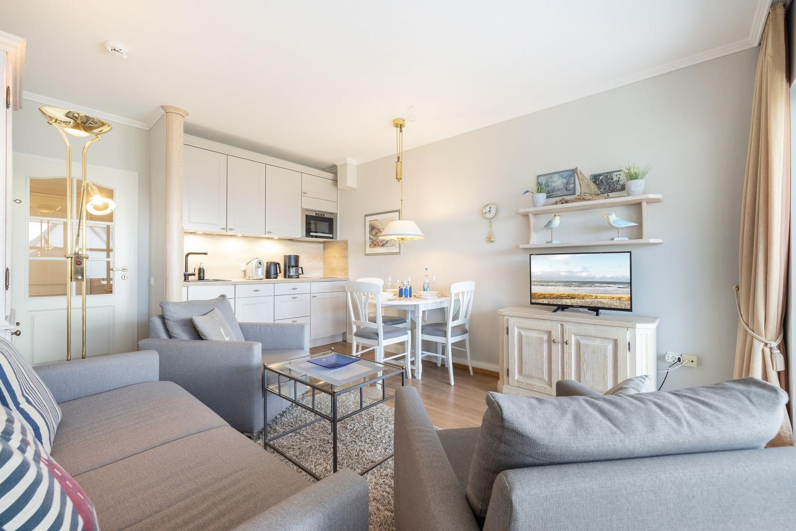 Wohnbereich mit Küchenzeile, Esstisch und Fernseher auf Sideboard.
