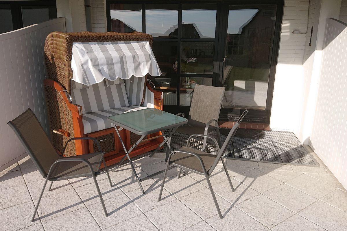 Terrasse mit Liege, Tisch und Stühlen vor Glasfront