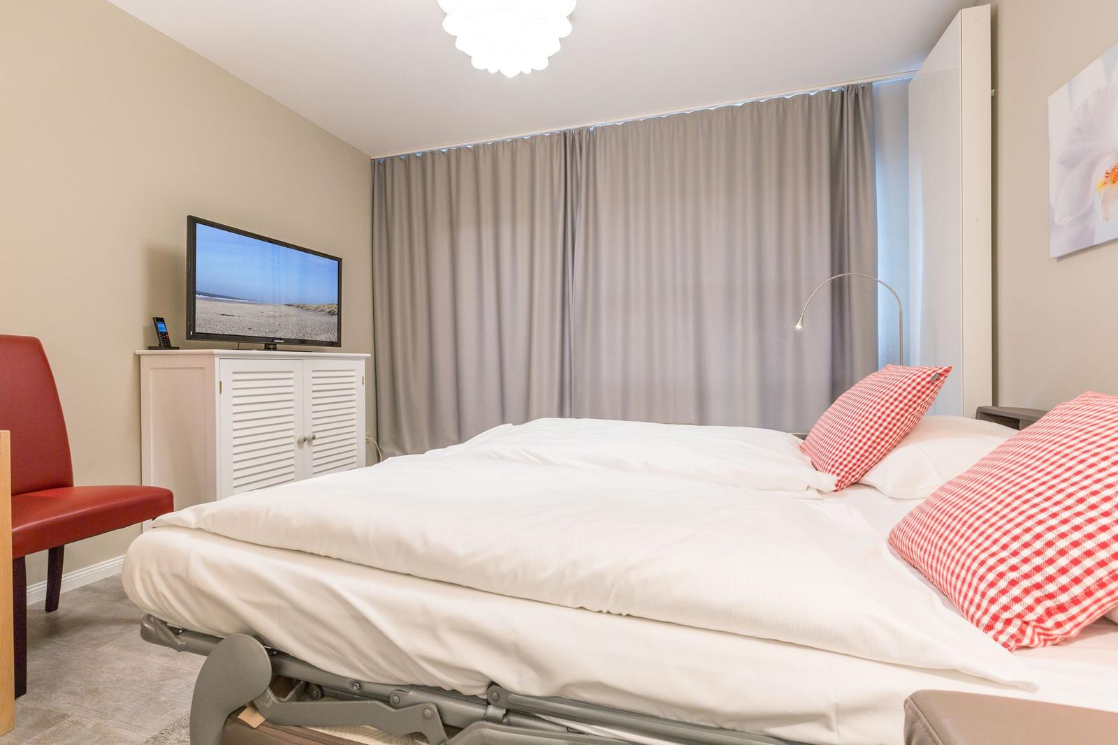 Bedroom with bed, TV, and red seating.