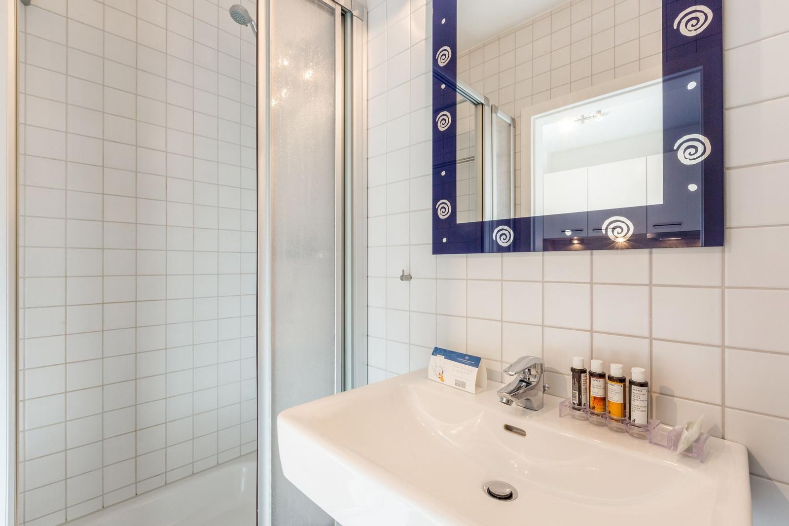 Bathroom with shower, sink, and mirror with blue frame.