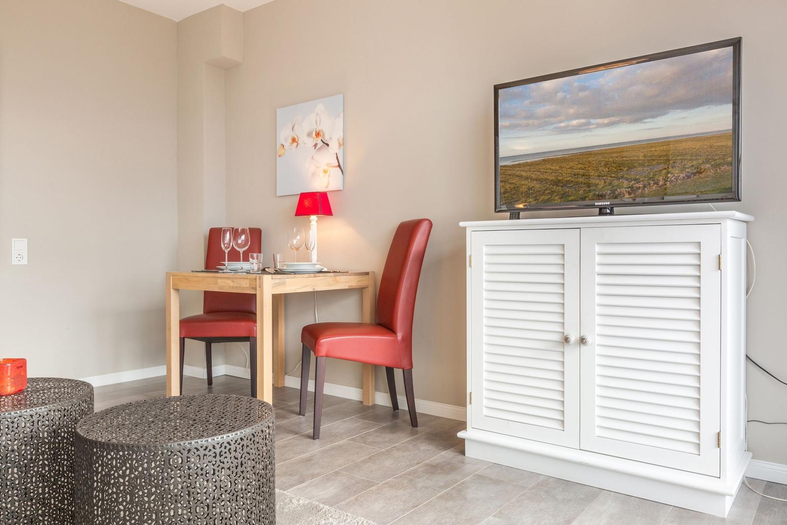 Dining area with table, two chairs, and TV on white cabinet
