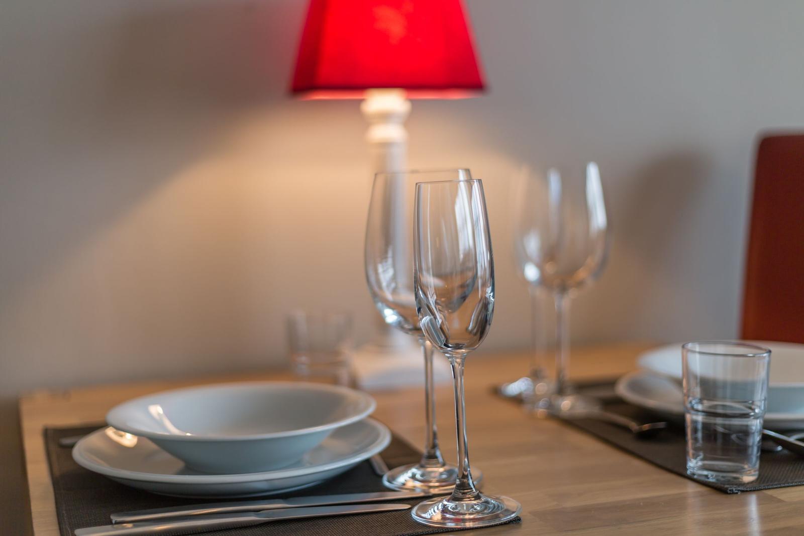 Table set with dishes, glasses, and a red lamp