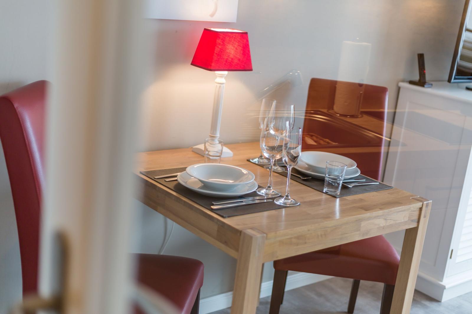 Dining table with two chairs, placemats, and a lamp.