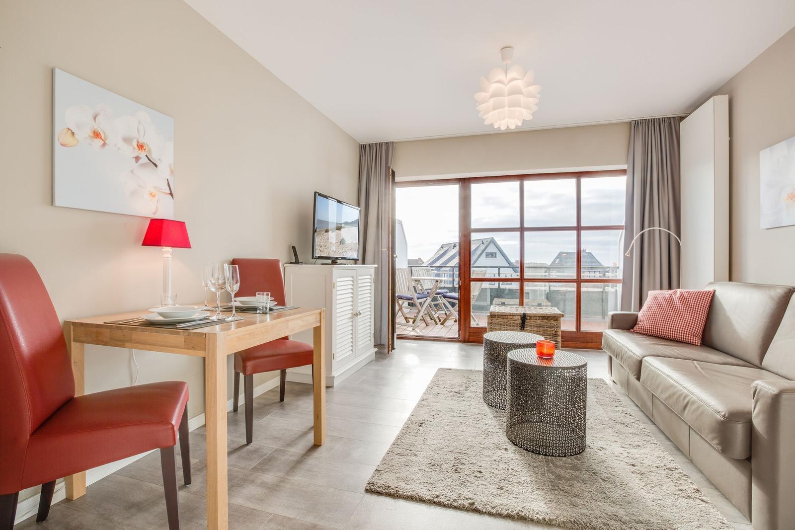 Living and dining area with balcony, sofa, dining table, and TV.