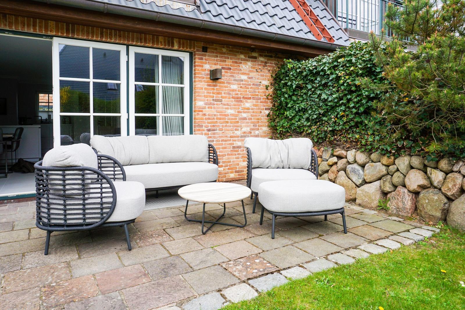 Terrace with seating group and table in front of brick house