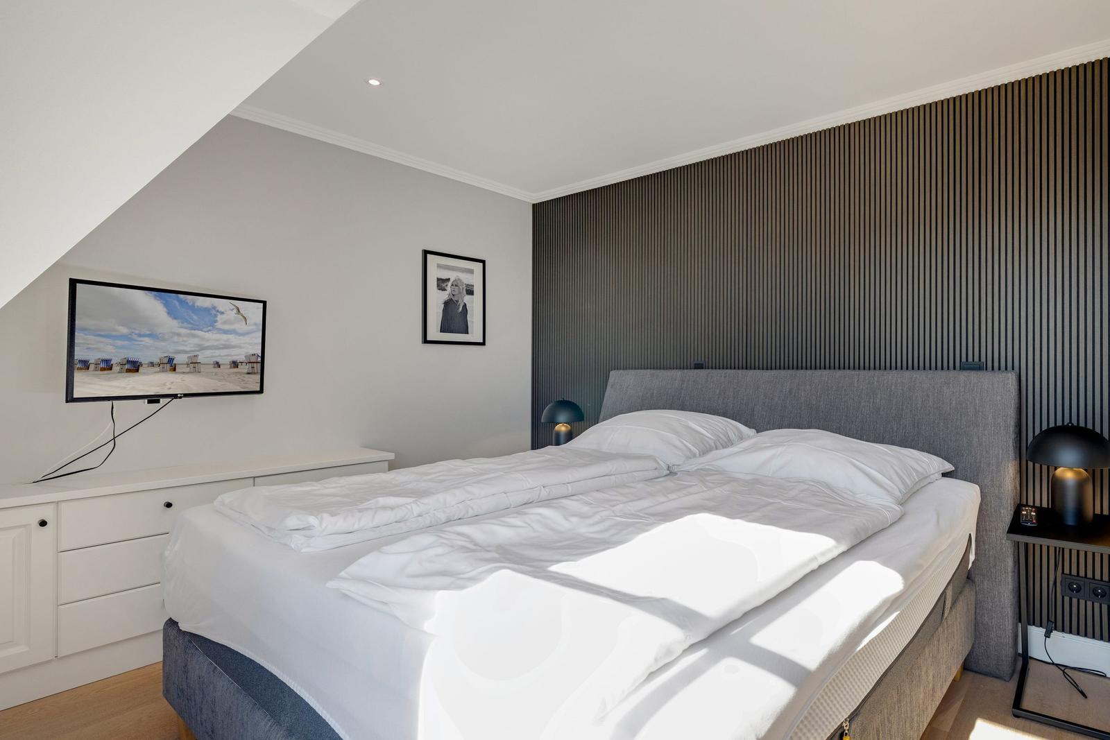 Bedroom with double bed, TV, and wooden wall