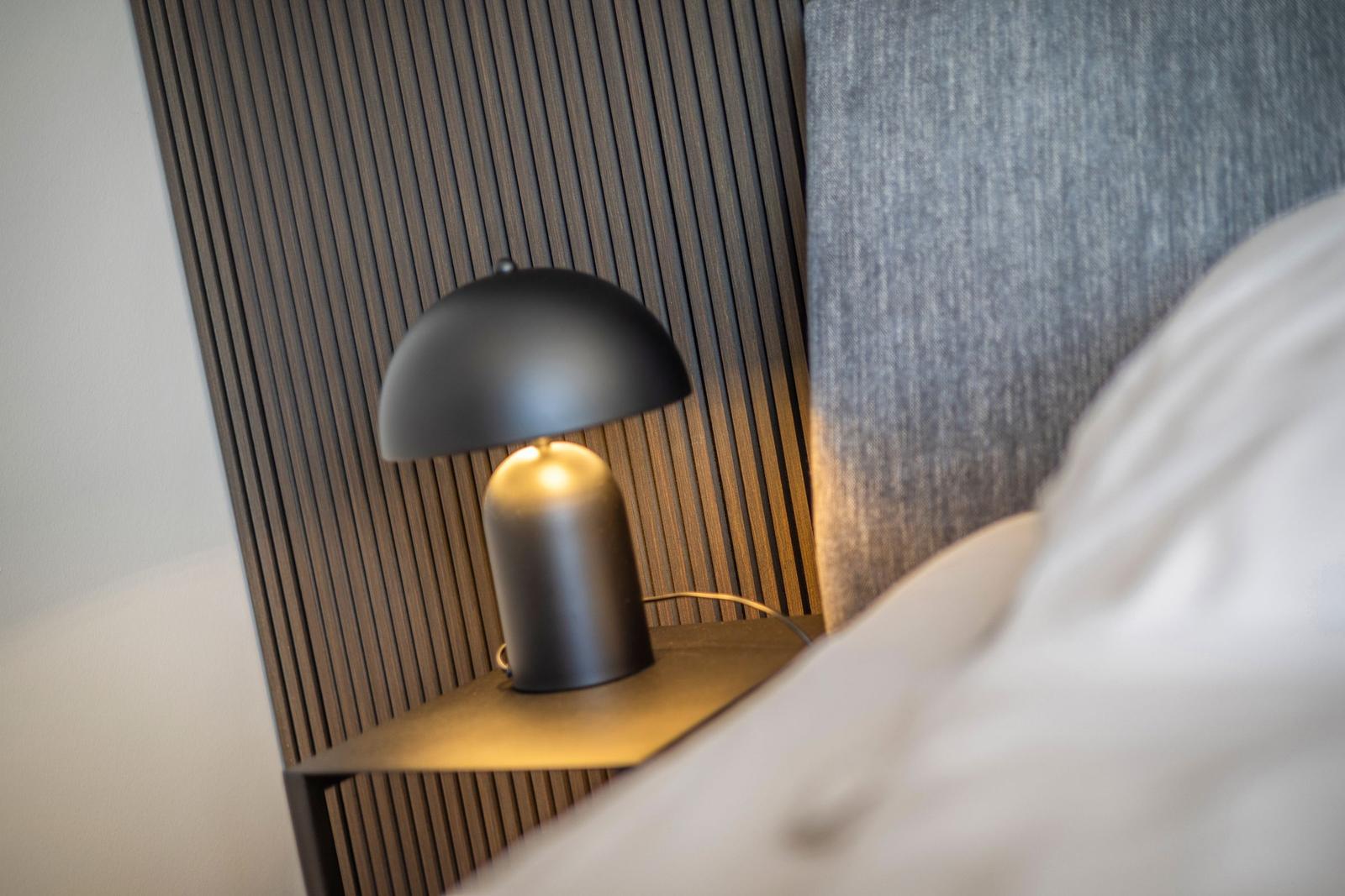 Bedroom with nightstand, lamp, and bed.