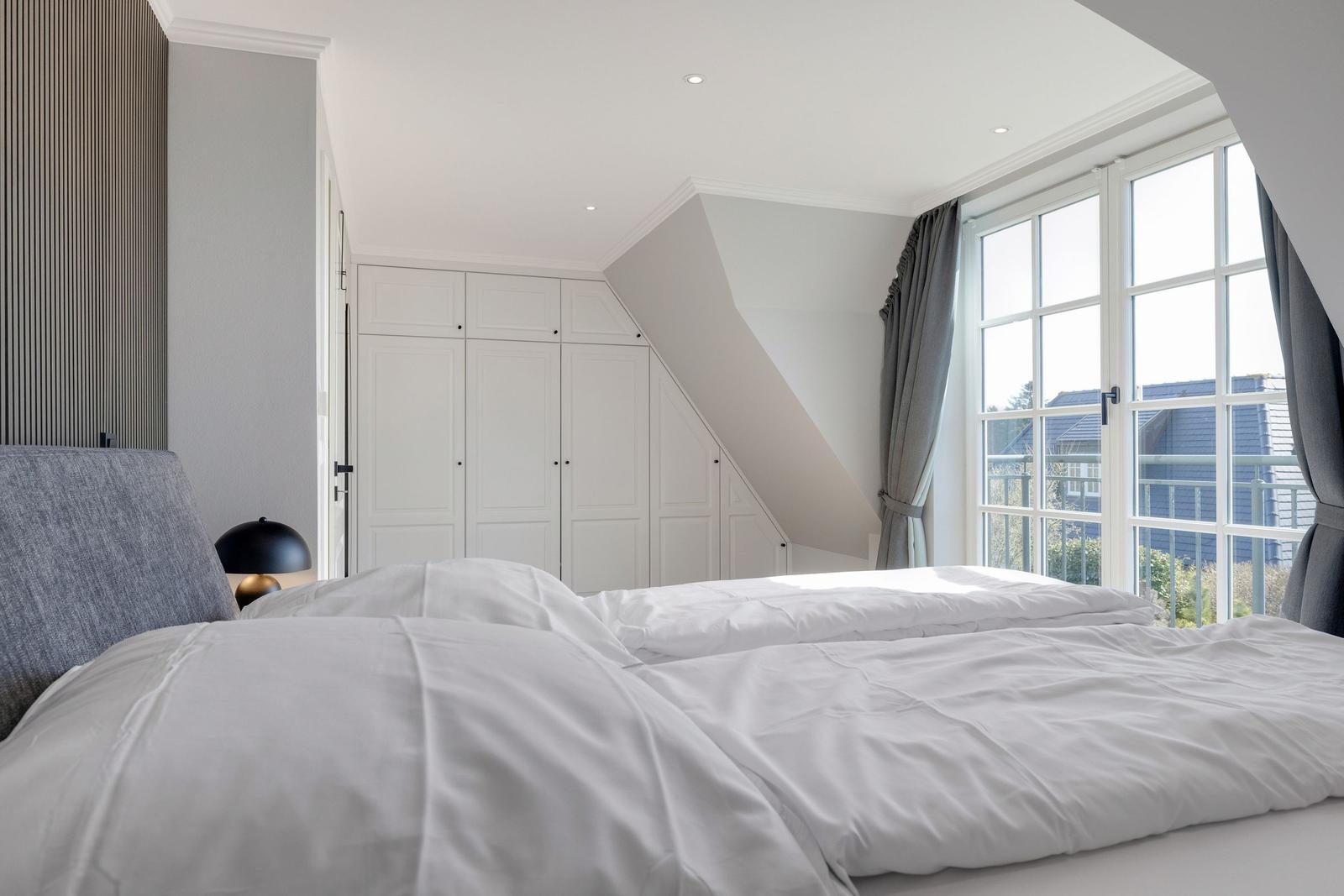 Bedroom with double bed, white wardrobes, and window with view.