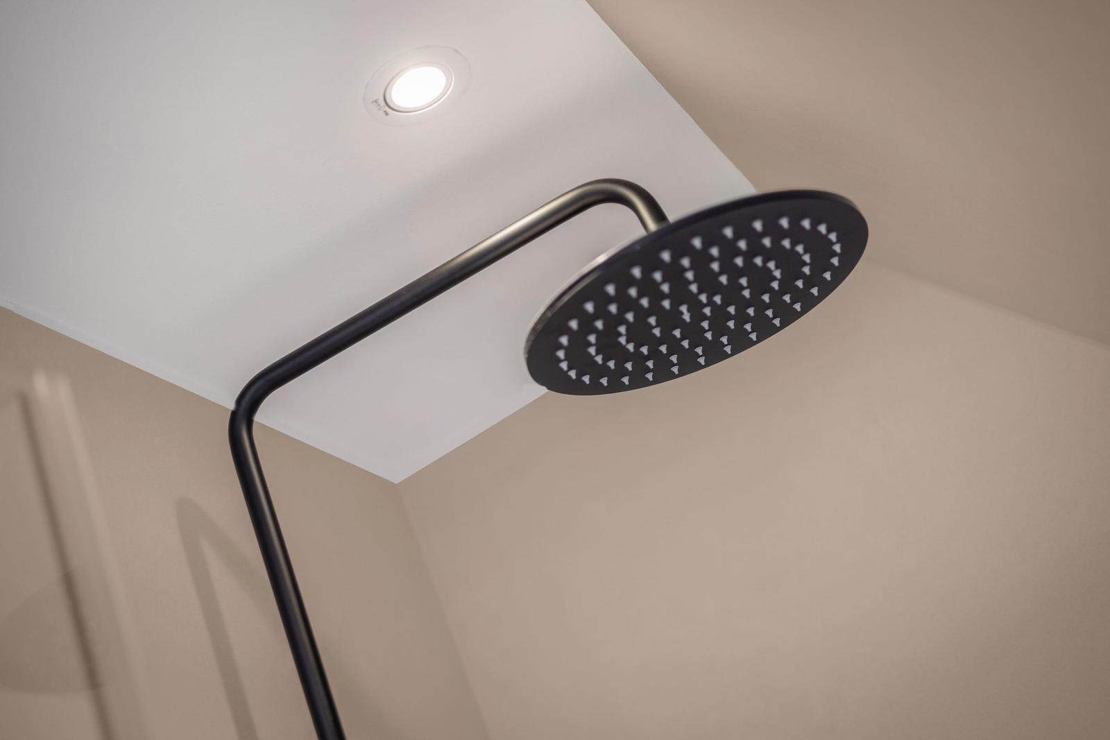 Shower head with black design mounted on ceiling.