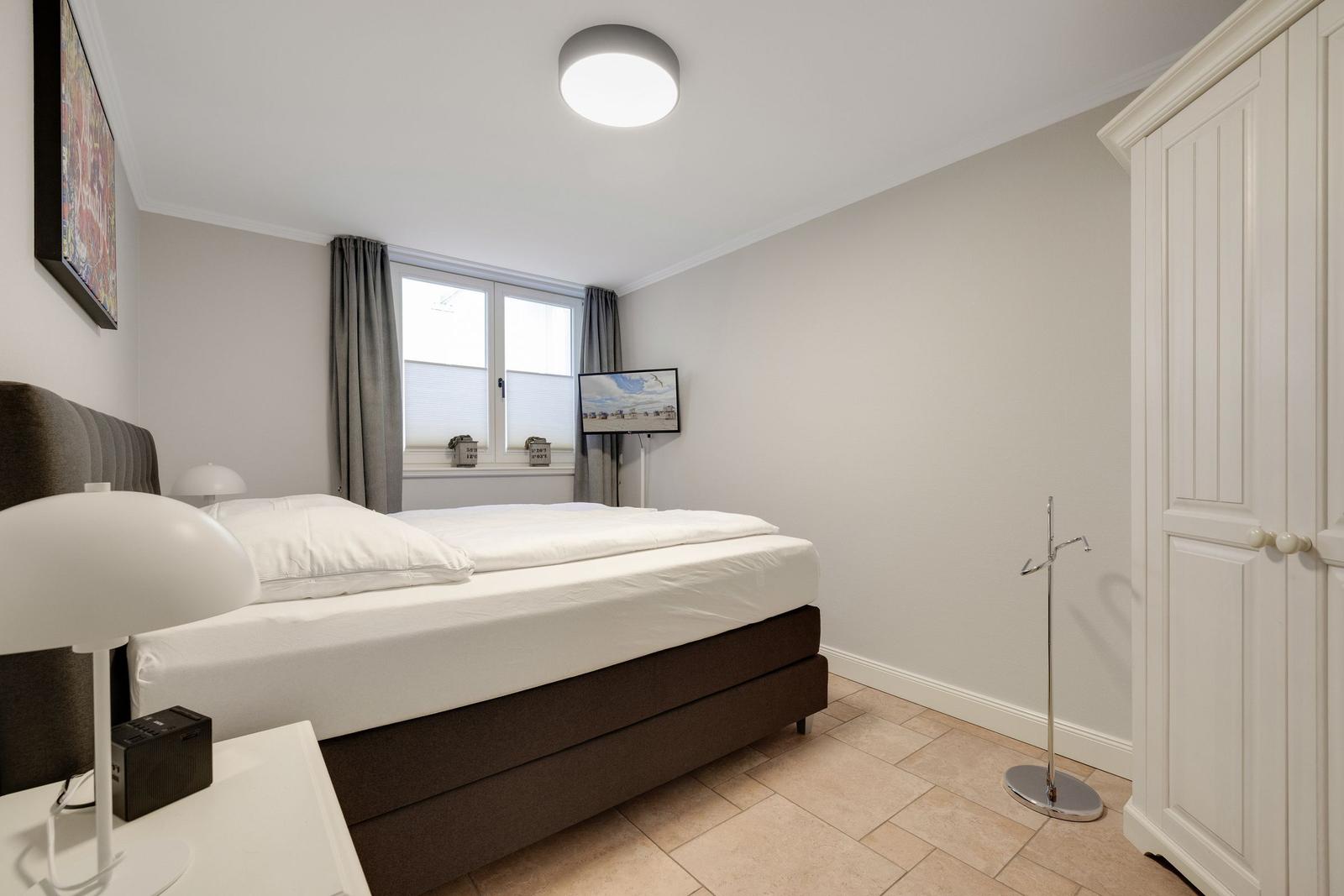 Bedroom with bed, window, wardrobe, and TV.
