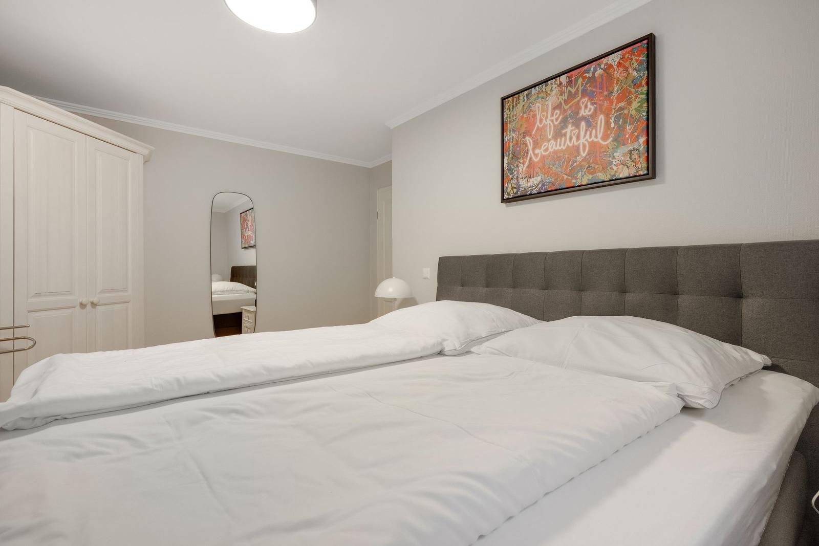 Bedroom with double bed, wardrobe, and wall art.