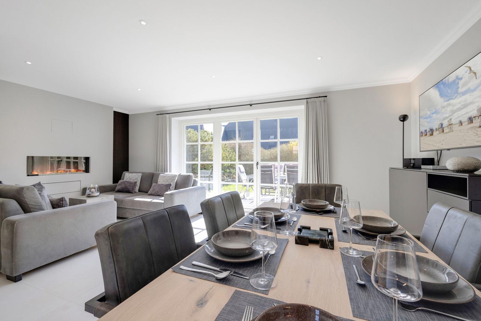 Dining area with table and chairs, living area with sofa and fireplace.
