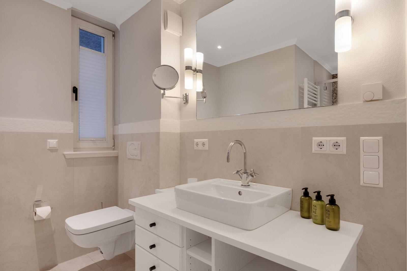 Bathroom with sink, mirror, and toilet.