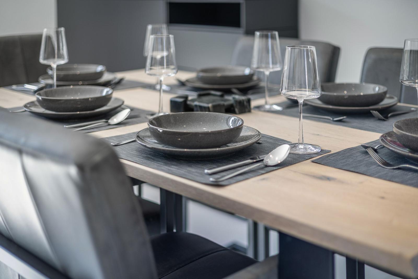 Dining room with wooden table, gray chairs, and tableware.