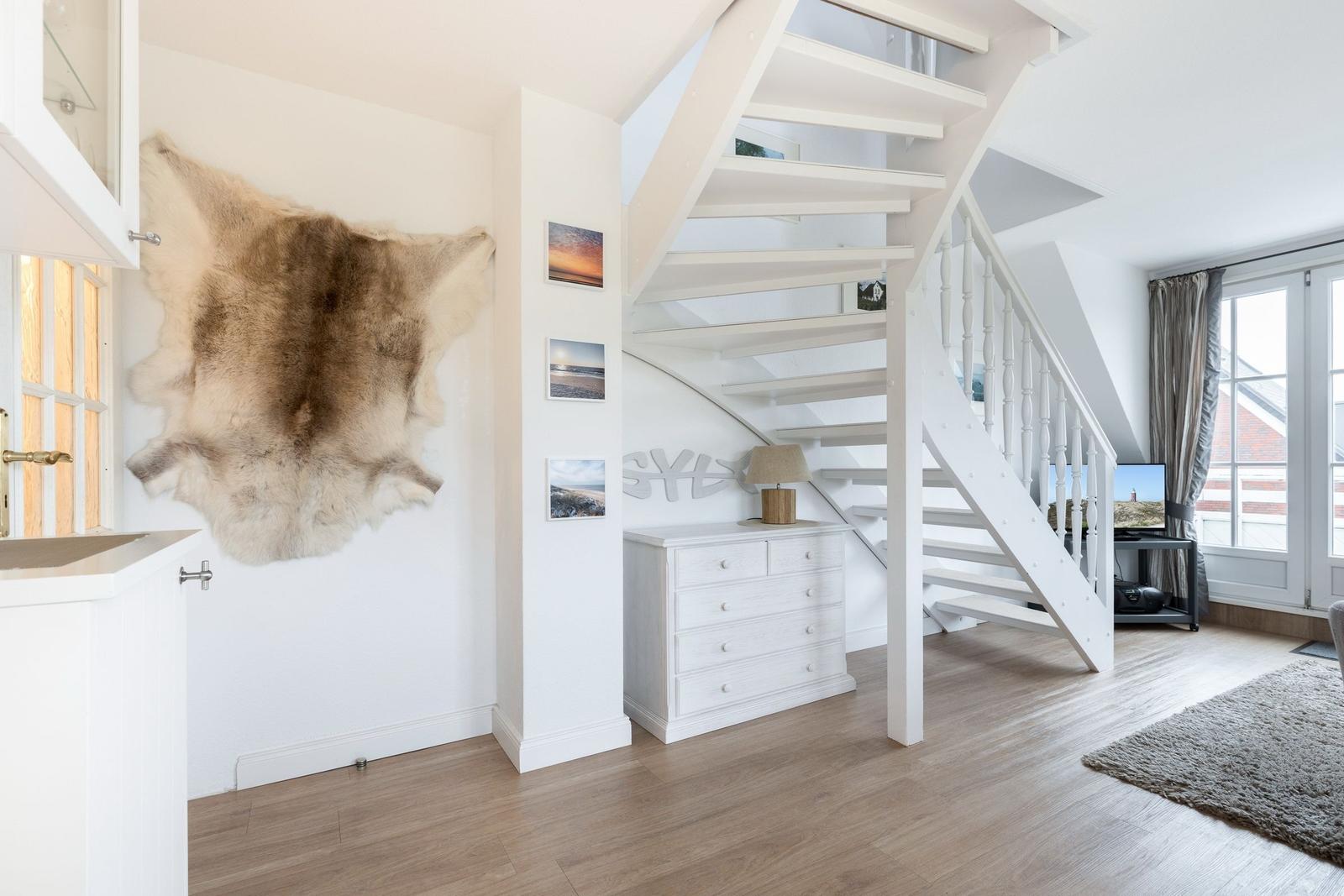 Bright rooms with wooden floors, white stairs, and fur on the wall.