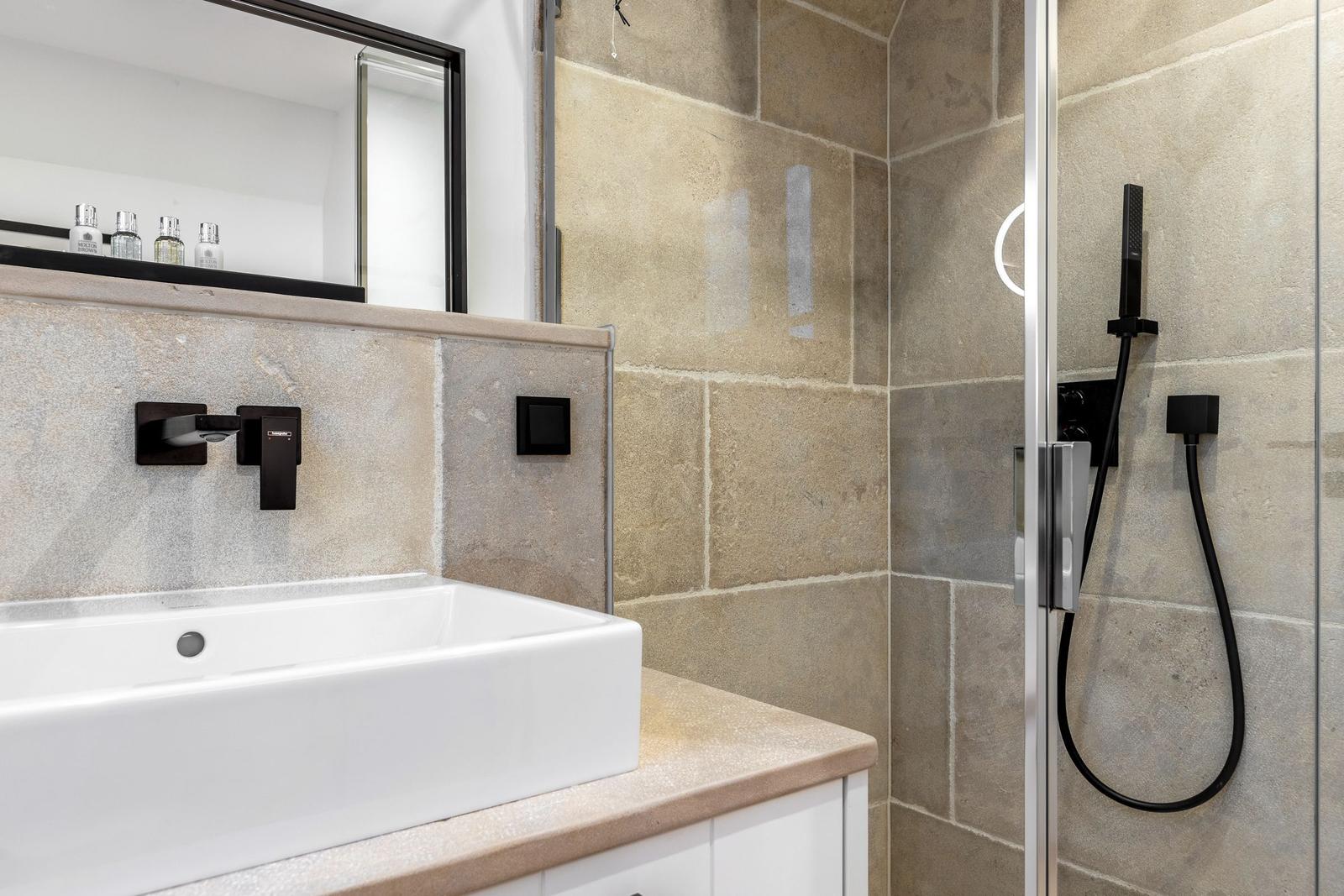 Badezimmer mit Waschbecken, Spiegel und Dusche mit Duschbrause