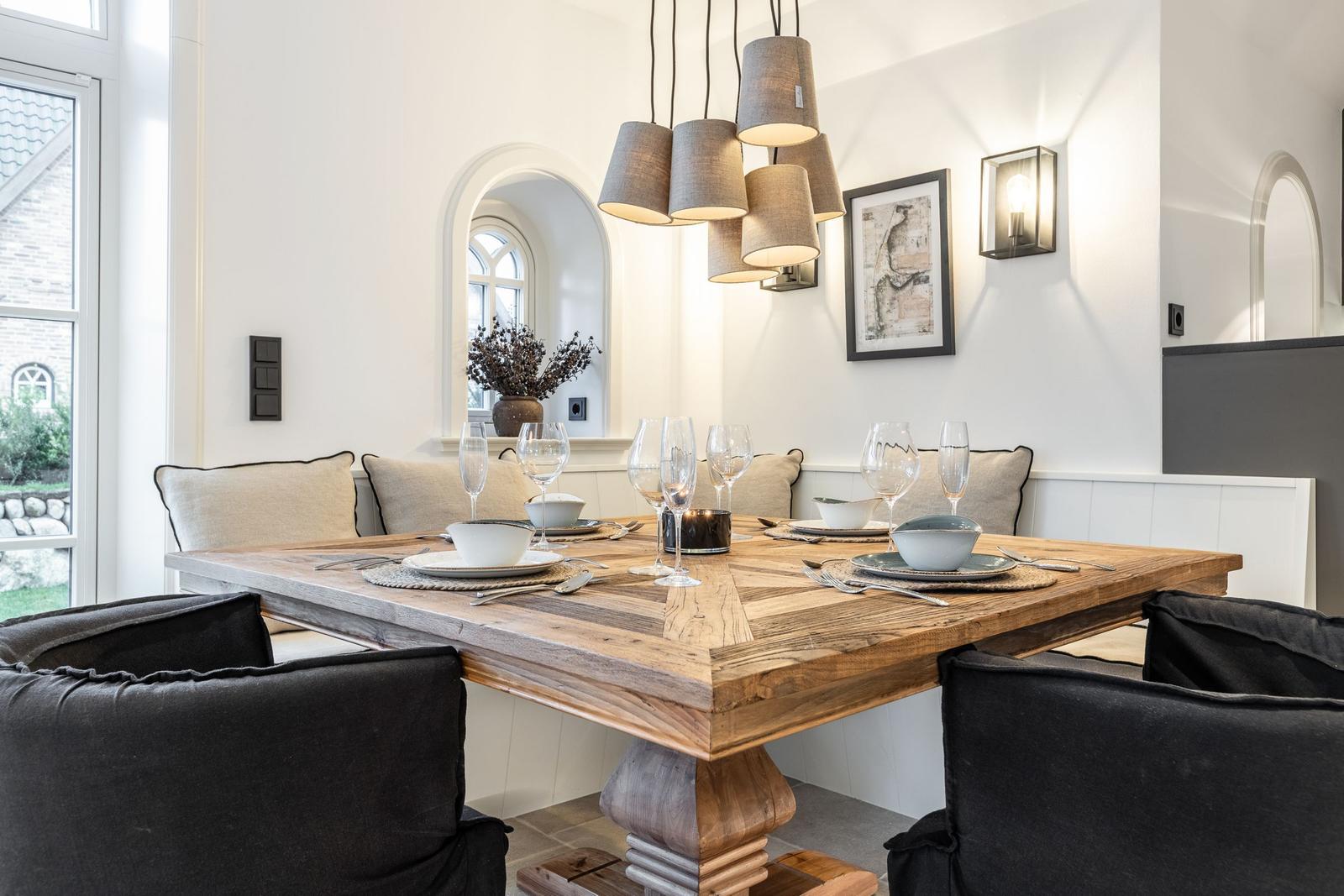 Esszimmer mit Holztisch, Stühlen und Deckenleuchte. Fenster und Wanddekoration sichtbar.