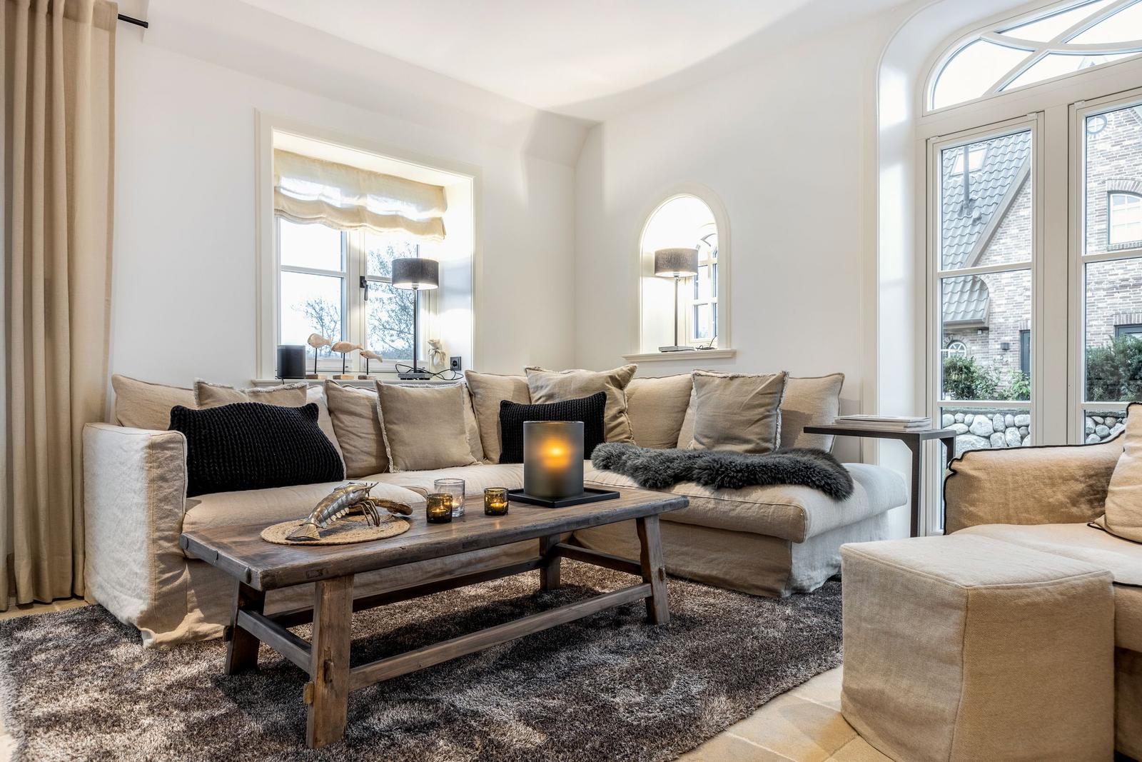 Wohnzimmer mit Sofa, Couchtisch und Fenstern.