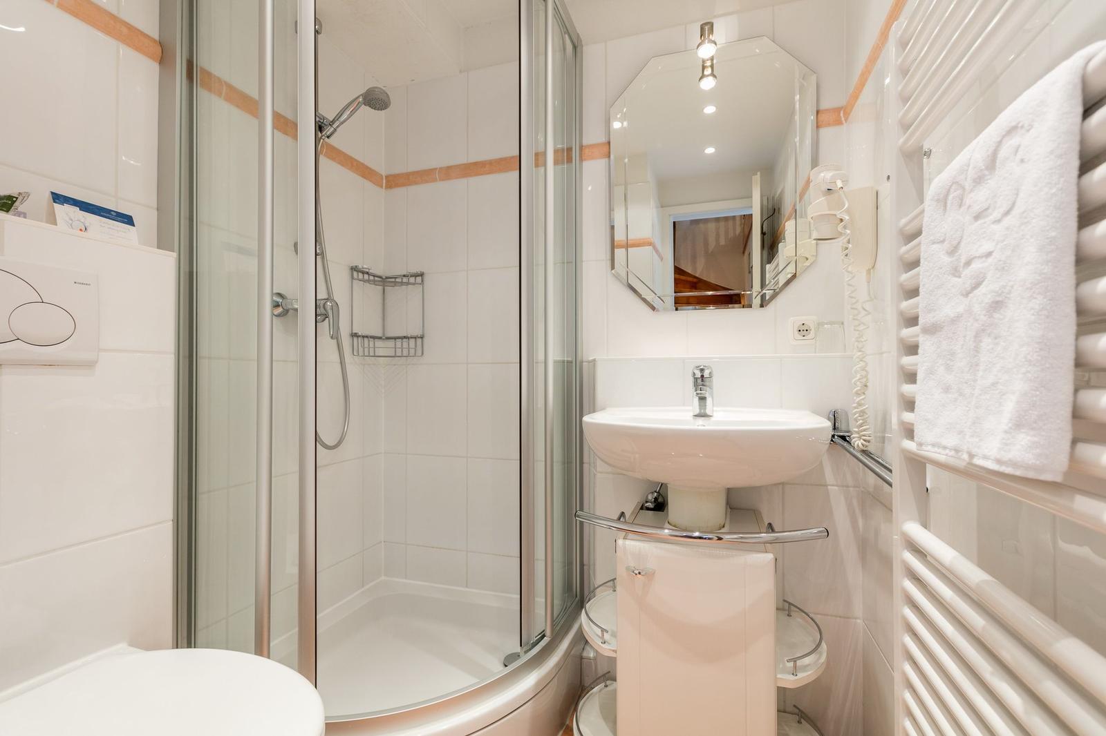 Bathroom with shower, sink, and towel warmer.