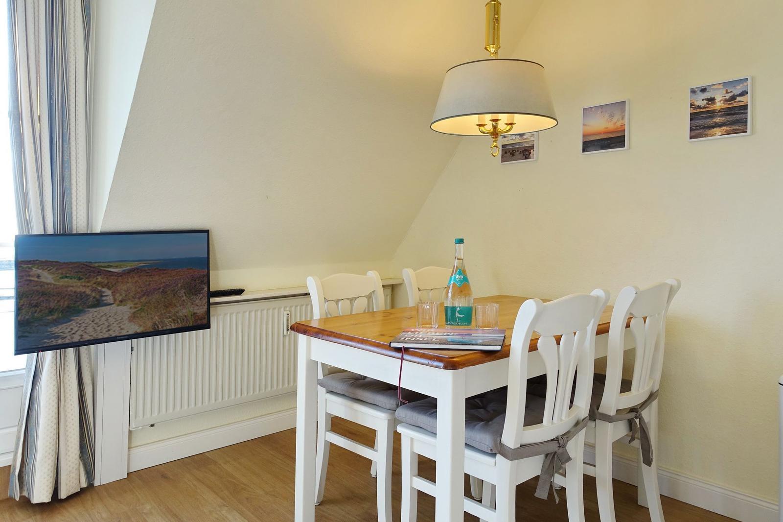 Dining area with table, chairs, and TV mounted on the wall.