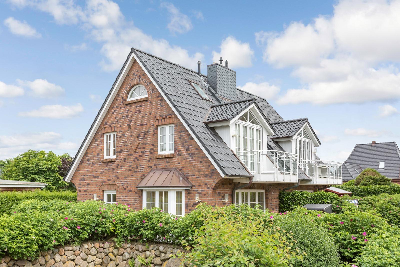 House with brick facade and balcony under blue sky