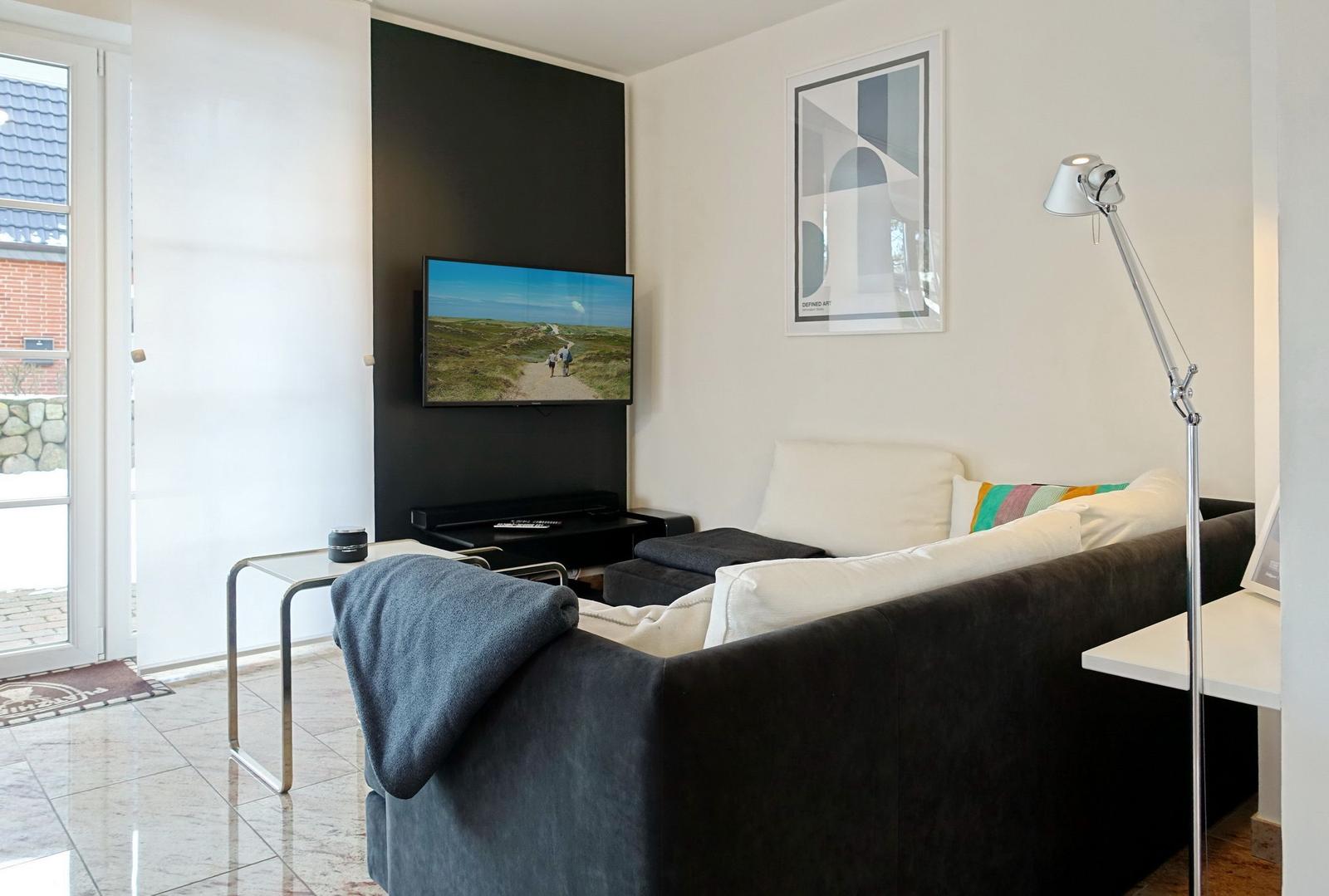 A living room with sofa, TV, and floor lamp.