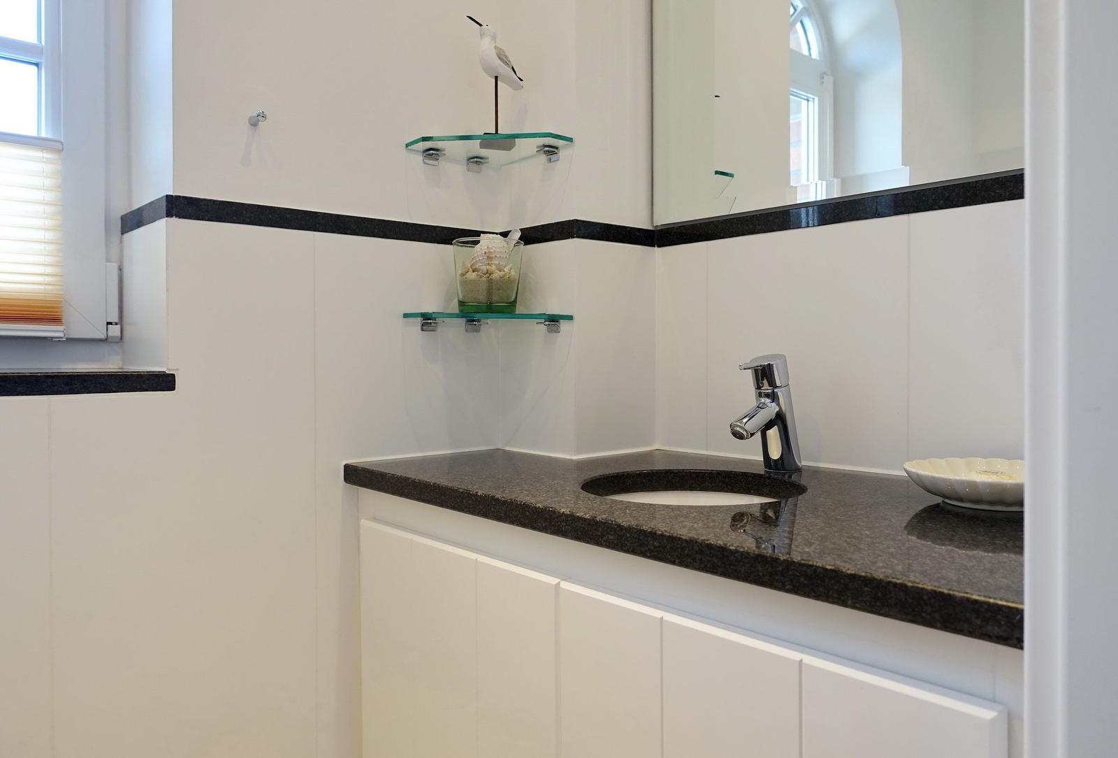 Bathroom with sink, mirror, and glass shelf with bird decoration.