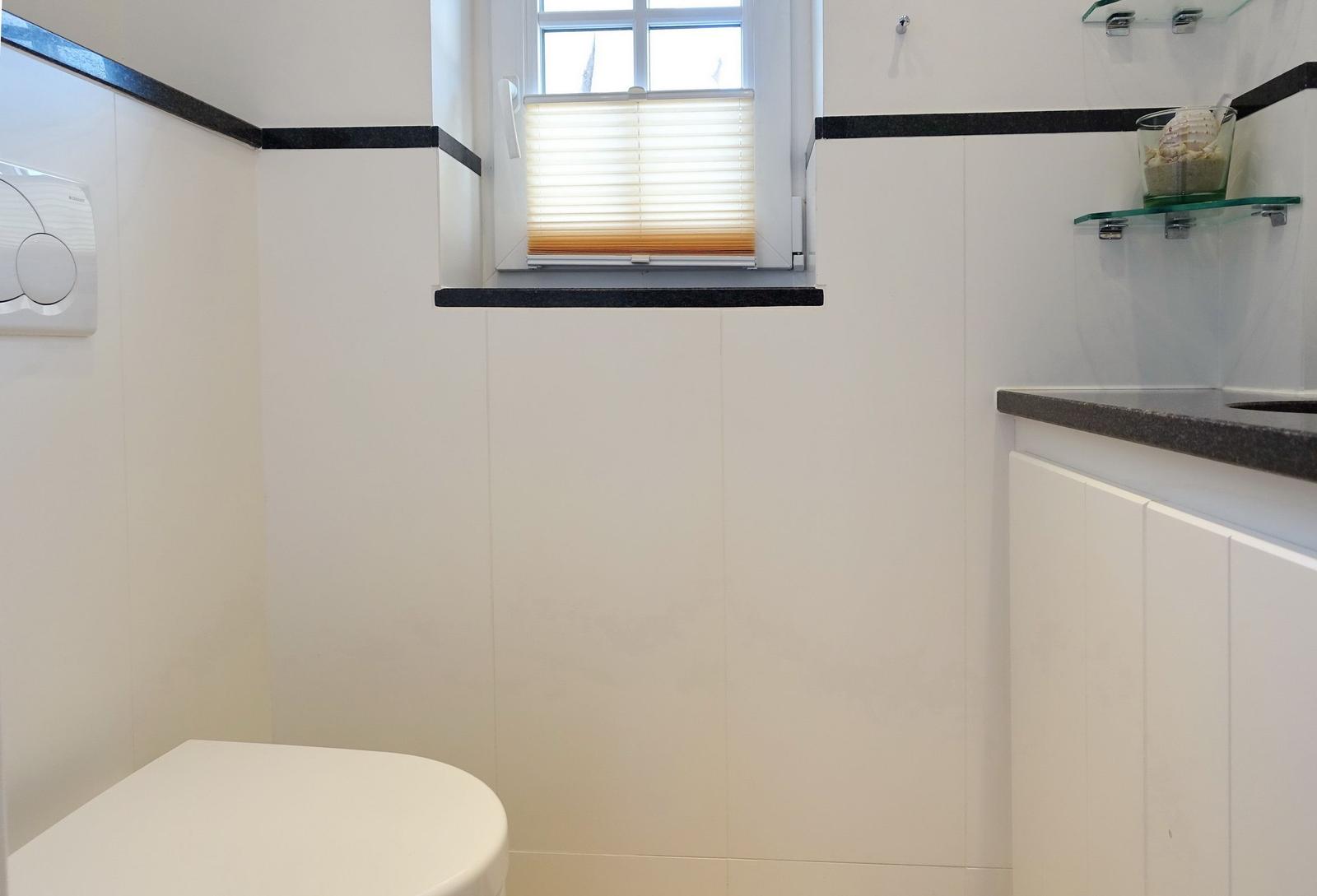 Bathroom with toilet, sink, and window with blinds.