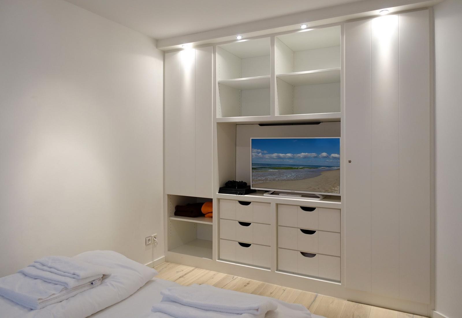 Bedroom with white closet, TV, and bed with towels.