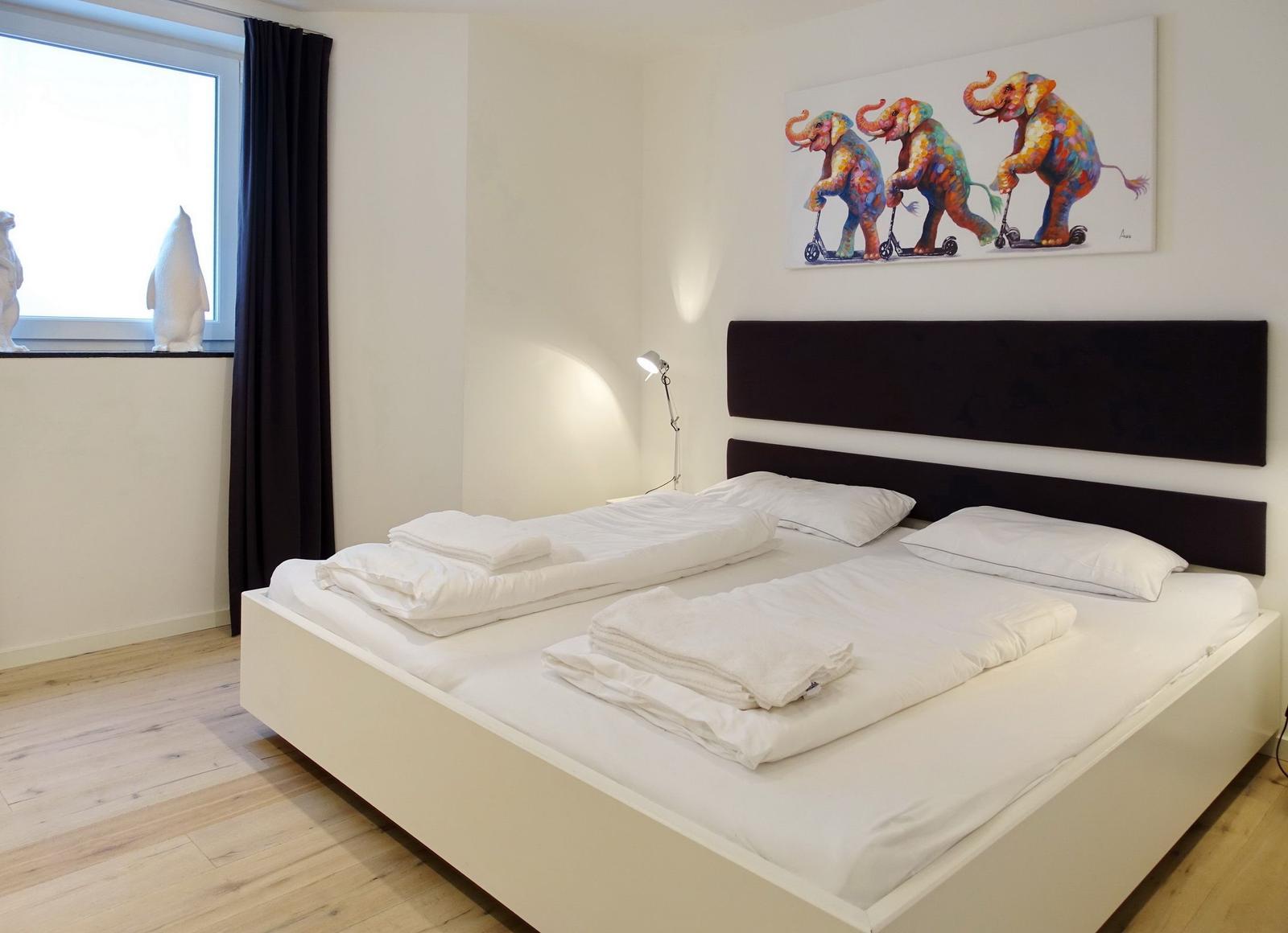 Bedroom with bed, wall art, and window with curtains.