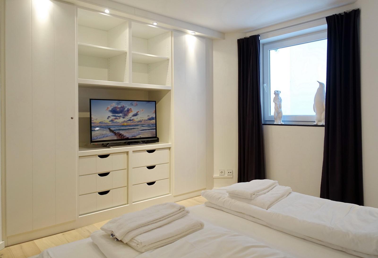Bedroom with bed, TV, and window with curtains.